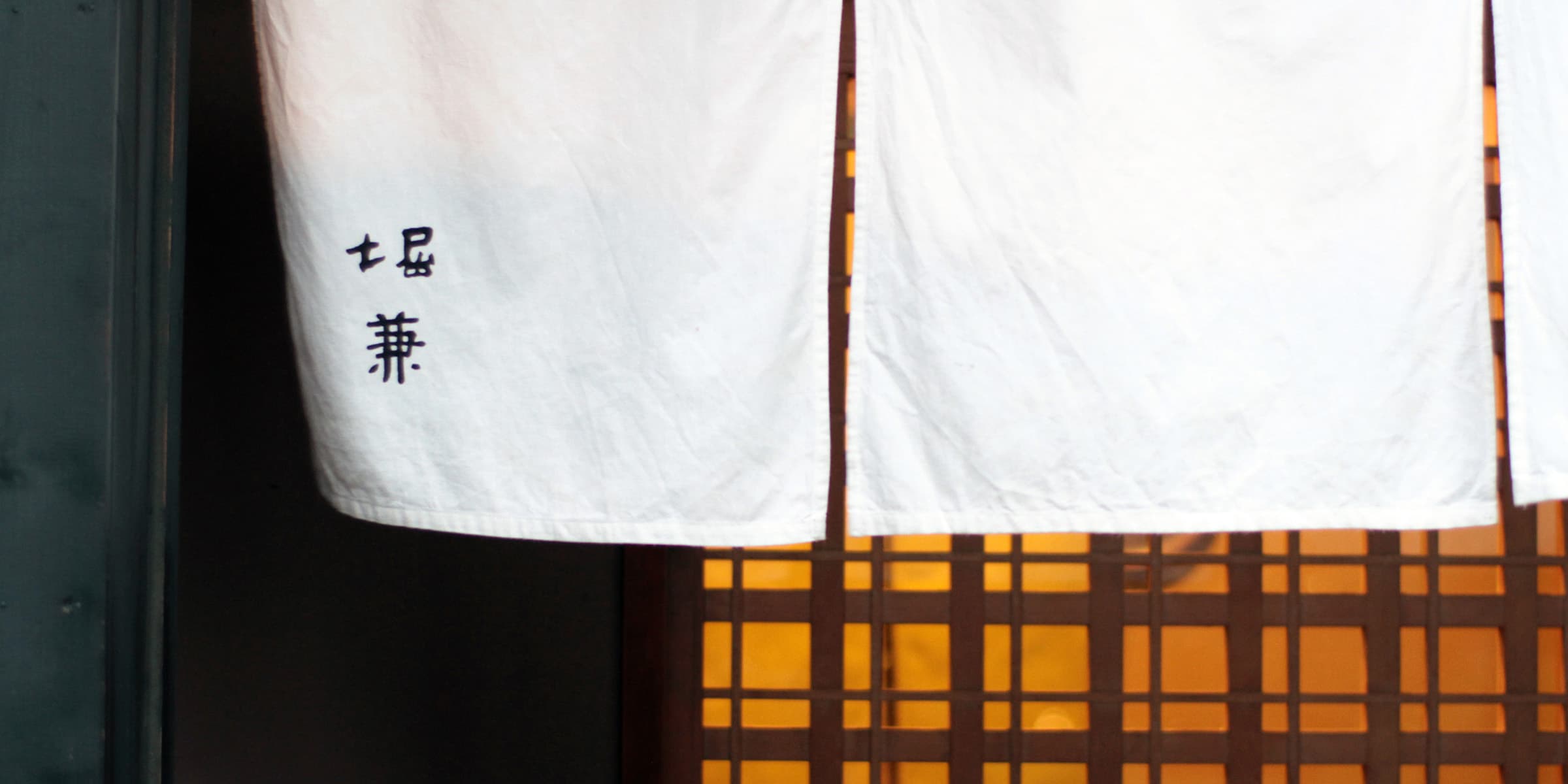 Horikane’s white noren curtain at its warmly lit entrance